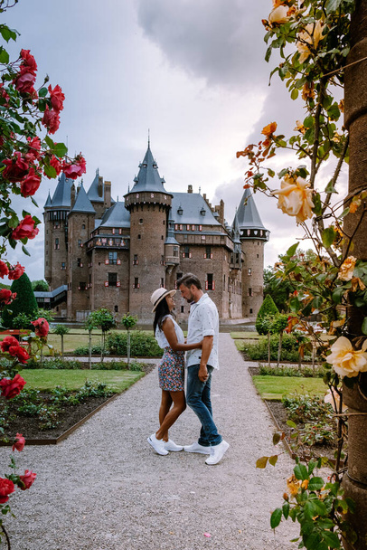 oude historische kasteeltuin, Kasteel de Haar Nederland Utrecht op een heldere zomerdag, jong stel mannen en vrouw van middelbare leeftijd wandelend in de kasteeltuin - Foto, afbeelding