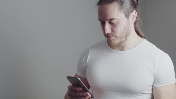 A male athlete, with a red beard, long hair, in a white T-shirt on a white background - Video, Çekim