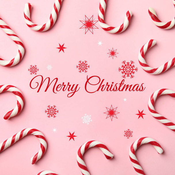 Flat lay composition with text MERRY CHRISTMAS and candy canes on pink background - Foto, Imagen