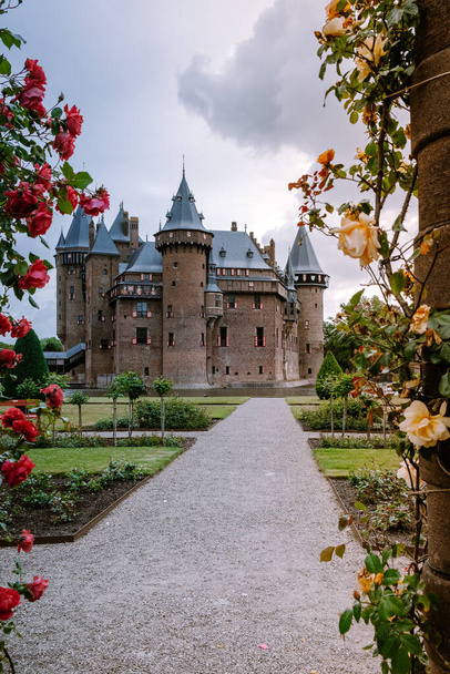 oude historische tuin bij Kasteel de Haar Nederland Utrecht op een stralende zomerdag, jong stel mannen en vrouw van middelbare leeftijd wandelen in de kasteeltuin - Foto, afbeelding