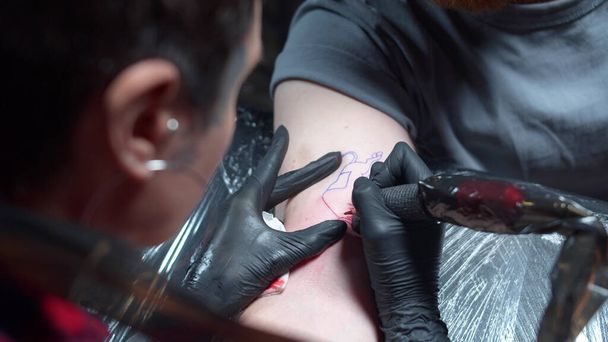 Uma mulher está enchendo uma tatuagem com uma máquina de tatuagem. Close-up
 - Foto, Imagem