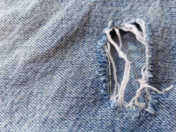 blauwe jean textuur met een gaatje en draden - Foto, afbeelding