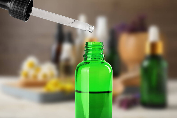 Little bottle with essential oil and dropper against blurred background  - Photo, image