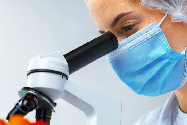 Woman scientist looking through a microscope in laboratory - Fotografie, Obrázek
