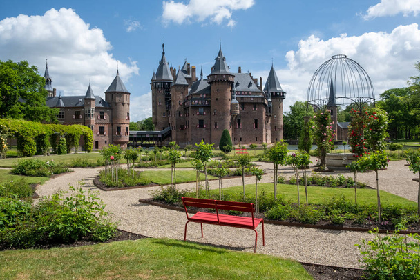 старый исторический сад в замке де Хаар Нидерланды Утрехт в яркий летний день, молодые пары мужчин и женщин среднего возраста прогулки в саду замка
 - Фото, изображение