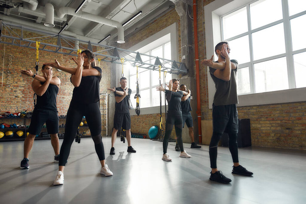 Love yourself enough to work harder. Full-length shot of diverse men and women working out together in industrial gym. Group training concept - Foto, Imagen