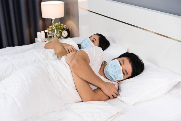 Hasta çift yatakta üşüyorlar ve koronavirüs için tıbbi maske takıyorlar (covid-19) - Fotoğraf, Görsel