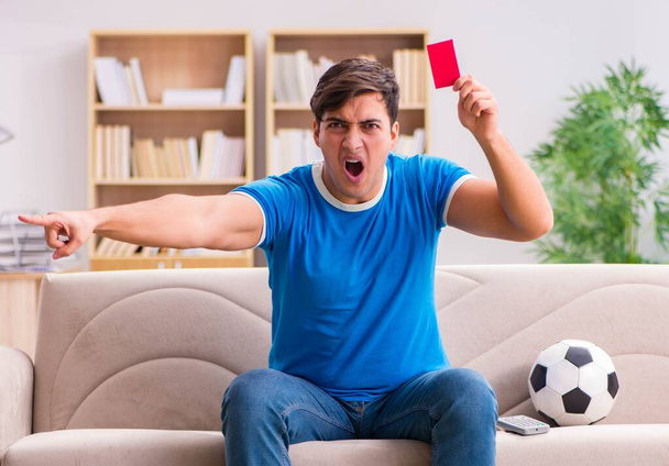 Мужчина смотрит футбол дома, сидя на диване - Фото, изображение