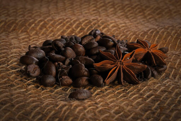 Schwarze geröstete Kaffeebohnen und Anissterne auf einem groben Tuch - Foto, Bild