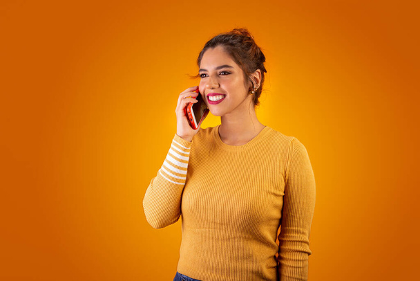 Femme sur fond jaune à l'aide d'un téléphone portable et souriant
 - Photo, image