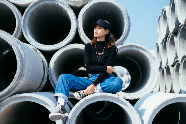 Portrait de jeune fille assise sur des tubes de ciment
. - Photo, image