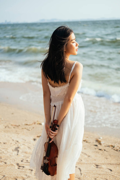Young woman and violin on the beach. - Фото, зображення
