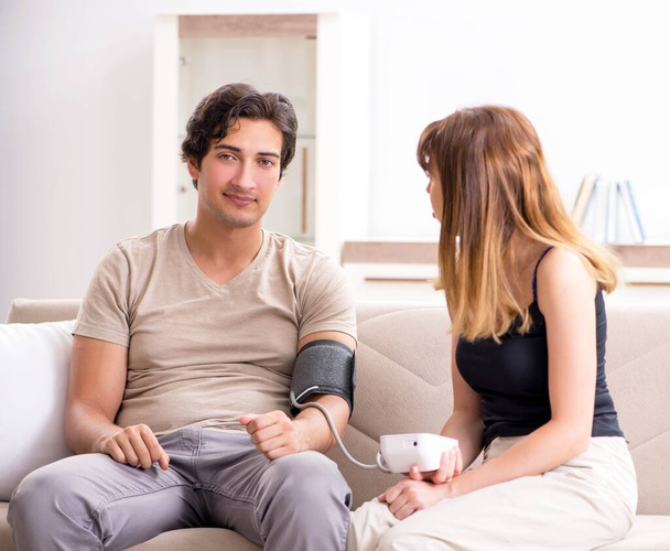 夫の血圧をチェックする妻 - 写真・画像