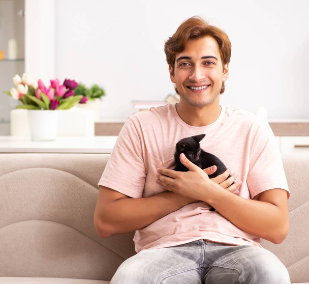 Nuori mies leikkii kissanpentu kotona - Valokuva, kuva