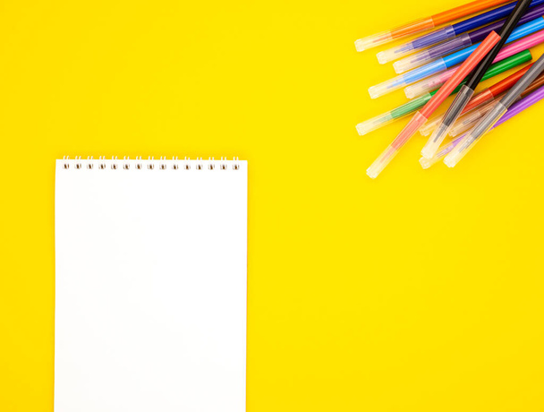 λευκό κενό σημειωματάριο με μαρκαδόρους σε κίτρινο φόντο, χώρος για κείμενο. Εκπαιδευτικά σχολικά είδη. Χαρτικά για το γραφείο. Πίσω στο σχολείο. online μάθηση - Φωτογραφία, εικόνα