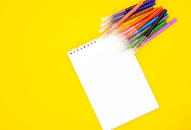 white blank Notepad with markers on a yellow background, space for text. educational school supplies. stationery for the office. back to school. online learning - Fotoğraf, Görsel