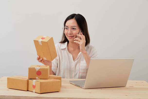 Szczęśliwa azjatycka kobieta pracuje z opakowania domu i zamówienia pisania z kartonu, na opakowaniu marketingu internetowego i dostawy, koncepcja MŚP - Zdjęcie, obraz