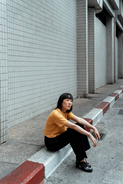 Supermodel assis sur un sentier à côté du mur de briques
. - Photo, image