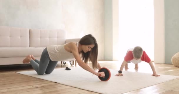 Mãe e filho fazendo exercícios esportivos em casa juntos no tapete na sala de estar
. - Filmagem, Vídeo