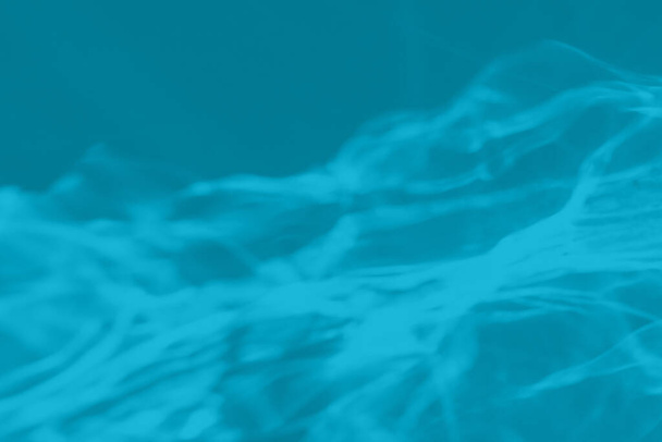 Mátově modrá barva s nízkým kontrastem abstraktní pozadí se světlem a stíny žíravý efekt. Světlo prochází sklem. Vodní pozadí. 2021 rok barevný trend - Fotografie, Obrázek