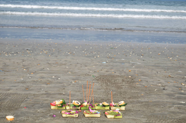 インドネシア・バリ島のクタビーチで海底砂の上に海の水の天使の神への犠牲の提供セットのバリニーズとインドネシアスタイルの儀式の提供 - 写真・画像