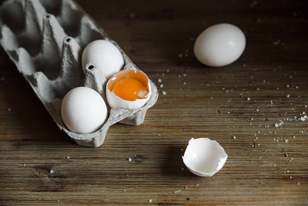 Fresh raw eggs in a tray with salt.Wooden background. - 写真・画像
