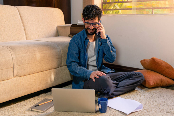 Ισπανόφωνος μιλάει στο τηλέφωνο τις ώρες εργασίας στο σπίτι του. Εργασία στο σπίτι έννοια. - Φωτογραφία, εικόνα