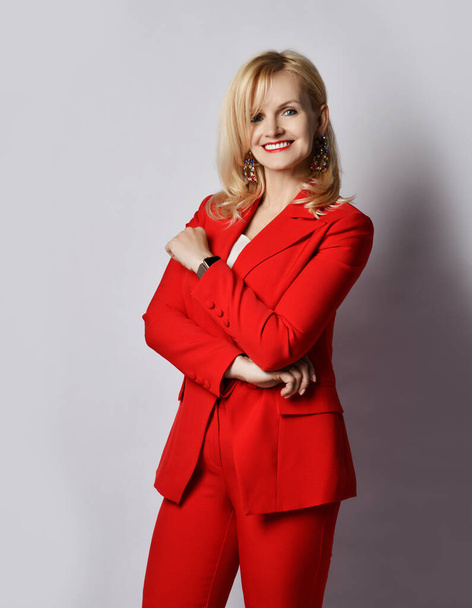 Portrait of young blond smiling businesswoman in stylish elegant deep red official suit and massive earrings  - Foto, Imagen