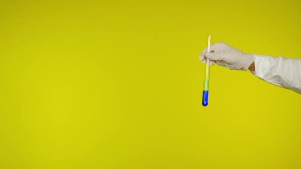 Ruka v latexové rukavici ochrana ukazuje skleněnou trubici s modrou látkou - Záběry, video