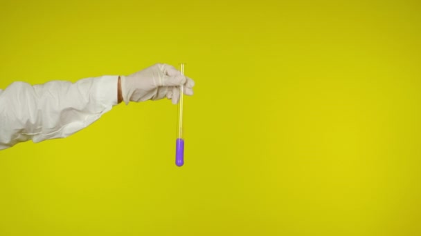Ręka w rękawicy ochronnej pokazuje szklaną rurkę z fioletową substancją - Materiał filmowy, wideo