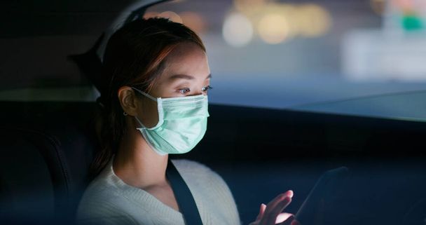 Donna indossare maschera medica e l'uso del cellulare in città di notte - Foto, immagini