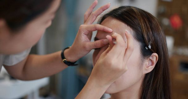 Make up artist shaping eyebrow on female model at studio - Zdjęcie, obraz