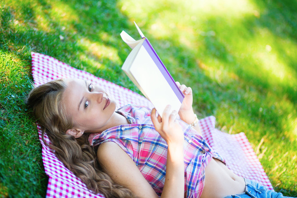 Girl lying on the grass and reading - Фото, изображение