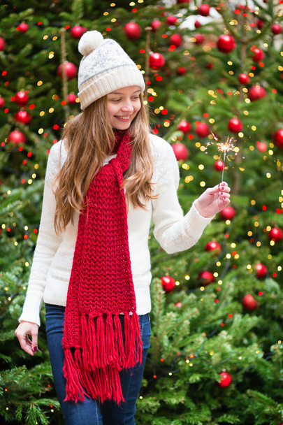 Girl with a sparkler near Christmas tree - 写真・画像