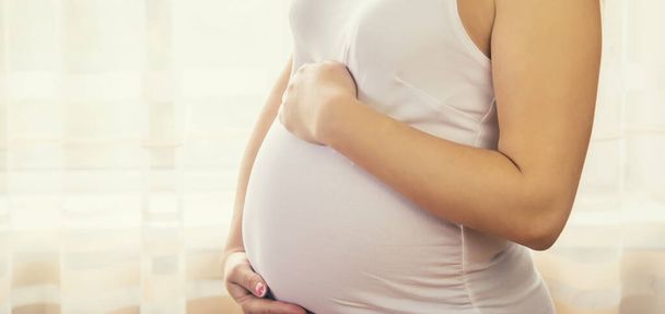 Беременная женщина обнимает живот. Селективный фокус. люди. - Фото, изображение