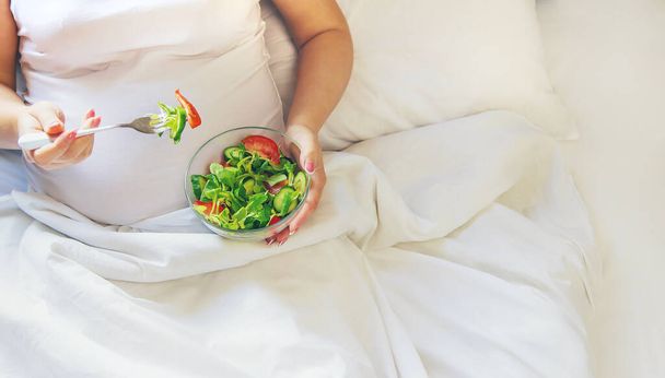 A pregnant woman eats a salad with vegetables. Selective focus. Food. - Fotografie, Obrázek