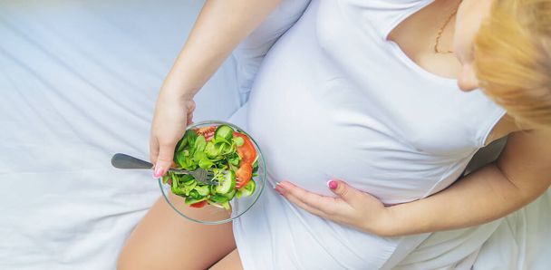 A pregnant woman eats a salad with vegetables. Selective focus. Food. - Fotografie, Obrázek