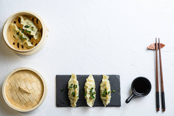 concept hinese snacks. chinese steamed dumpling Japanese gyoza or dumplings snack in wooden steamer and served on black slate with soy sauce Chinese Traditional cuisine top view space for text - Φωτογραφία, εικόνα