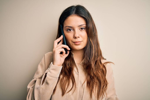 Fiatal gyönyörű barna nő beszélgetnek az okostelefonon egy magabiztos kifejezés okos arc gondolkodás komoly - Fotó, kép