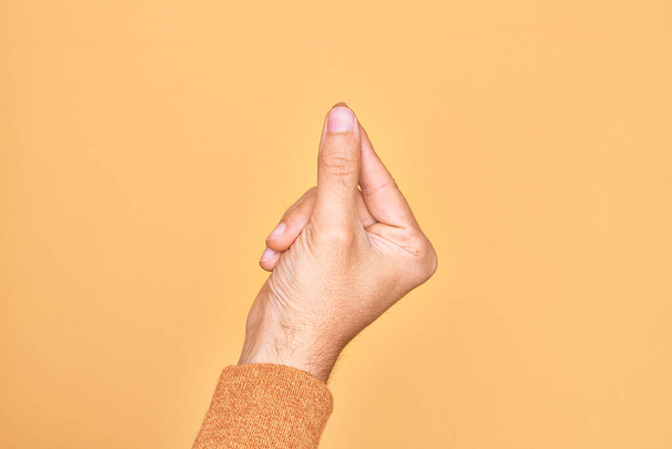 ręka kaukaski młody człowiek pokazując palce na odizolowanym żółtym tle trzymając puste miejsce z kciukiem palec, biznes i reklama - Zdjęcie, obraz