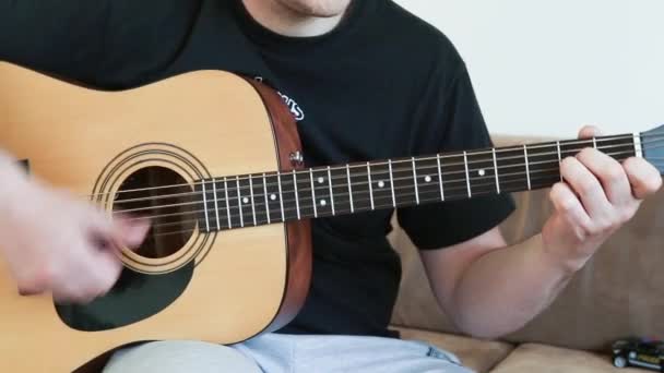 Egy fickó akusztikus hathúros gitáron játszik. megtanulnak játszani egy hangszeren közelkép. - Felvétel, videó