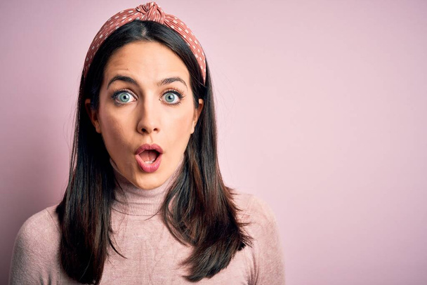 Young brunette woman with blue eyes wearing casual t-shirt and diadem afraid and shocked with surprise expression, fear and excited face. - Photo, Image