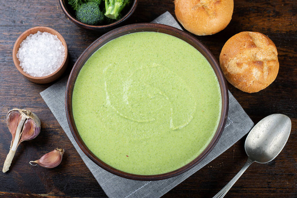green vegetable cream soup broccoli in a plate on the table. next to it are fresh buns and an inflorescence of Borkcol - Foto, imagen