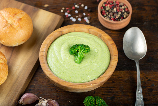 green broccoli cream vegetable soup in a wooden plate on the table. soup decorated with broccoli inflorescenc - Foto, Imagem