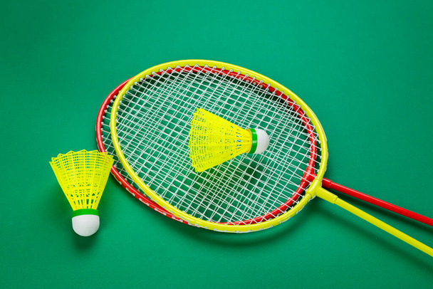 two badminton rackets with a shuttlecock lie on a green backgroun - Foto, afbeelding