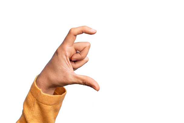 Hand eines kaukasischen jungen Mannes mit Fingern über isoliertem weißem Hintergrund, der unsichtbare Dinge pflückt und nimmt, während er ein Objekt mit Fingern hält, die Raum zeigen - Foto, Bild