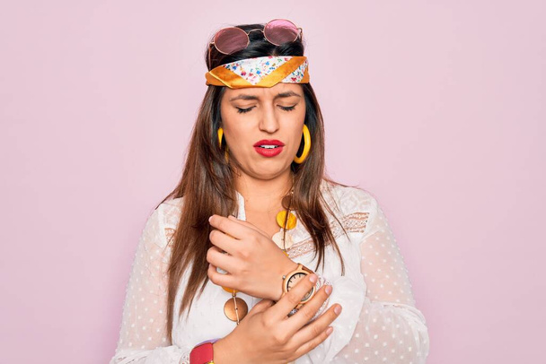 Genç İspanyol hippi kadın pembe arka planda moda boho stili ve güneş gözlüğü takıyor. Ellerinde ve parmaklarında ağrı var. Eklem iltihabı. - Fotoğraf, Görsel