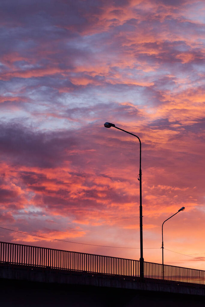 Sunset sky with brigh colorful clouds and black silhouette brige, road with lanters and fence, abstract elegant minimalistic landscape. - Photo, image
