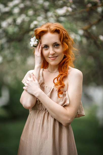 red-haired girl in a blooming garden - Fotografie, Obrázek