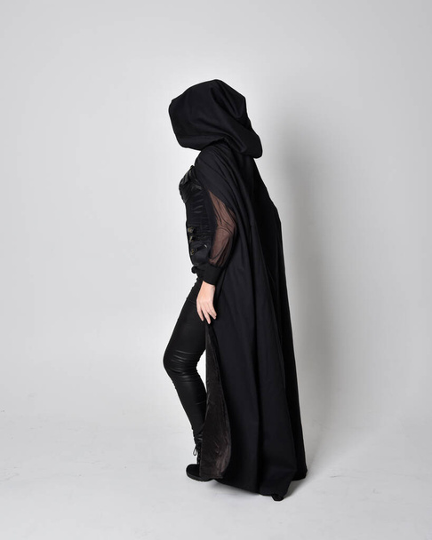 portrait imaginaire d'une femme portant un long manteau noir. pose debout sur toute la longueur avec dos à la caméra, isolé sur un fond de studio
. - Photo, image